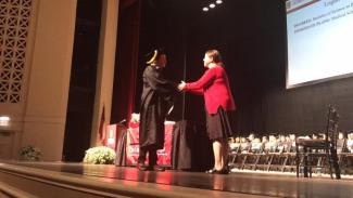 Dr. Miller shaking hands with graduate Logan