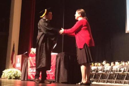 Dr. Miller shaking hands with graduate Logan